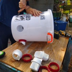 A man drilling holes into a white bucket.